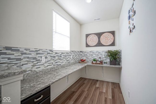interior space featuring decorative backsplash, visible vents, light stone countertops, and wood finished floors | Image 24