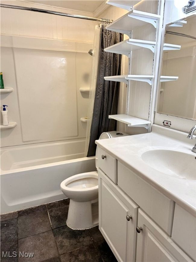 Full bathroom featuring stone tile floors, vanity, shower / bathtub combination with curtain, and toilet | Image 14