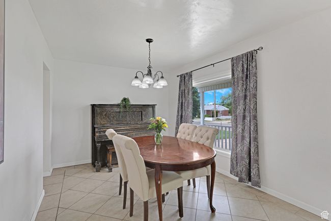 Dining area with a chandelier, light tile patterned floors, and baseboards | Image 10