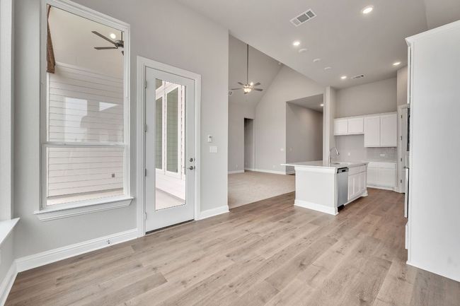 Kitchen with a ceiling fan, white cabinets, open floor plan, stainless steel dishwasher, and a center island with sink | Image 13