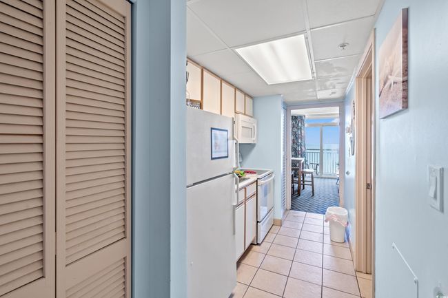 Kitchen with white appliances, light tile patterned flooring, and a wall of windows | Image 14