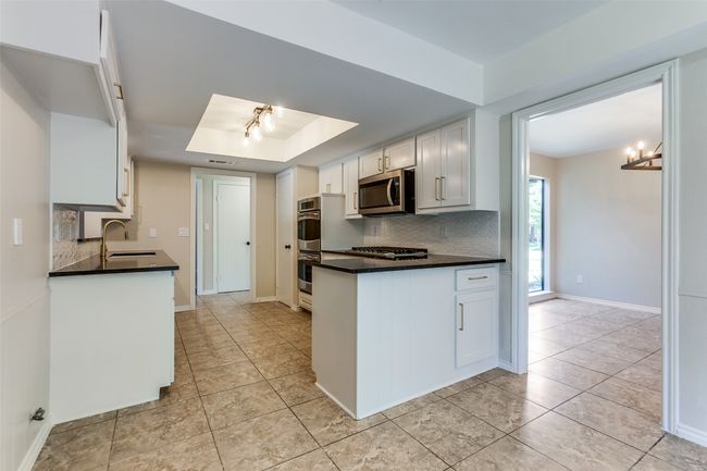 Kitchen featuring appliances with stainless steel finishes, decorative backsplash, and dark countertops | Image 12