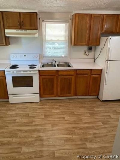 Kitchen featuring white appliances, sink, light hardwood / wood-style floors, and a textured ceiling | Image 2