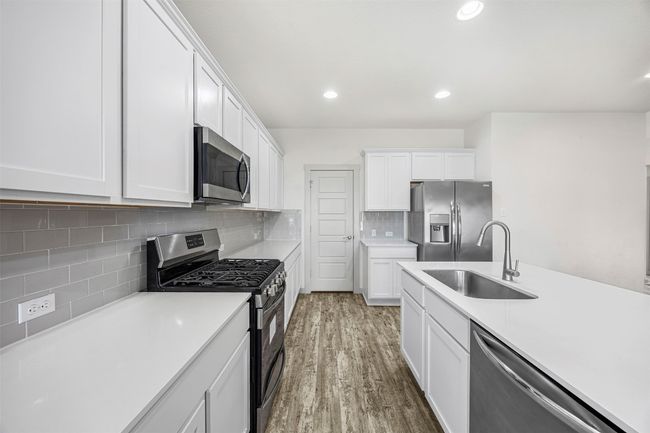 A chef's dream kitchen! Featuring sleek quartz countertops, modern white cabinetry, and stainless steel appliances, including a gas range and built-in microwave. | Image 11