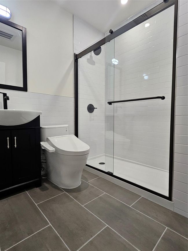 Bathroom with tile walls, vanity, a shower stall, toilet, and wainscoting | Image 22