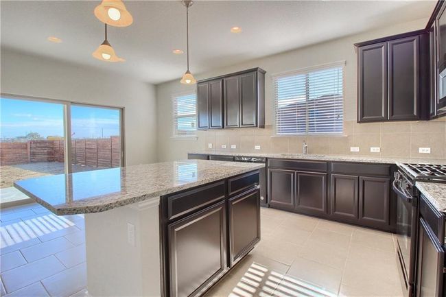 Kitchen with black range with gas cooktop, tasteful backsplash, light tile patterned flooring, light stone counters, and recessed lighting | Image 4