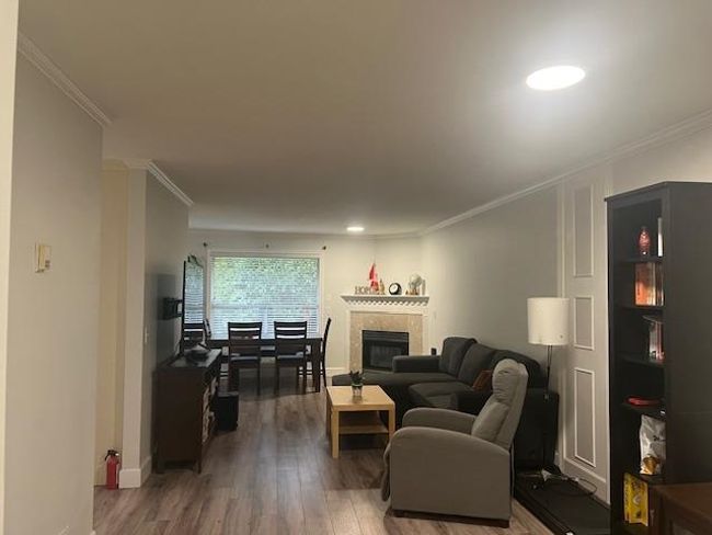 Living room featuring a glass covered fireplace, ornamental molding, baseboards, and wood finished floors | Image 4