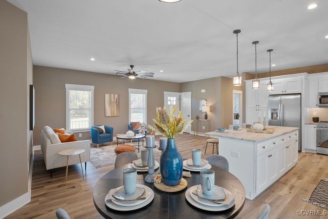Kitchen featuring light wood-style flooring, a ceiling fan, white cabinets, stainless steel appliances, and open floor plan | Image 8