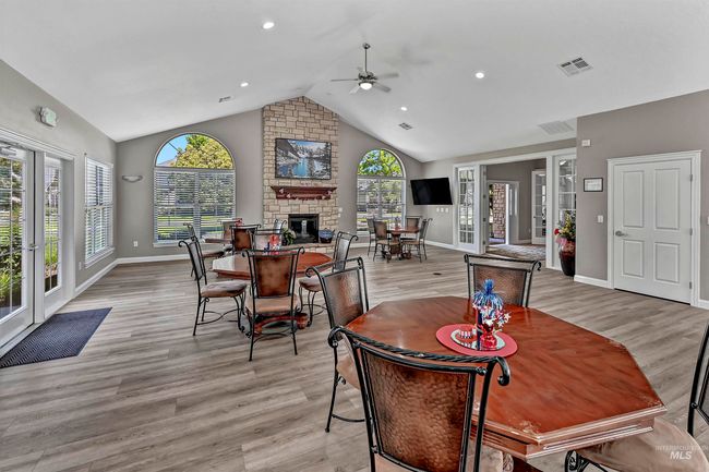 Dining area featuring a ceiling fan, a large fireplace, light wood-style floors, high vaulted ceiling, and recessed lighting | Image 27