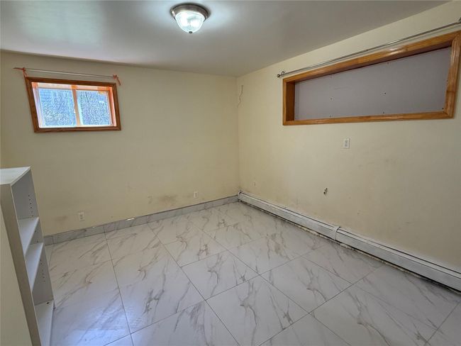 Basement with a baseboard radiator, baseboards, and marble finish floor | Image 15