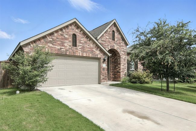View of front facade with brick siding, concrete driveway, a garage, and a front lawn | Image 4