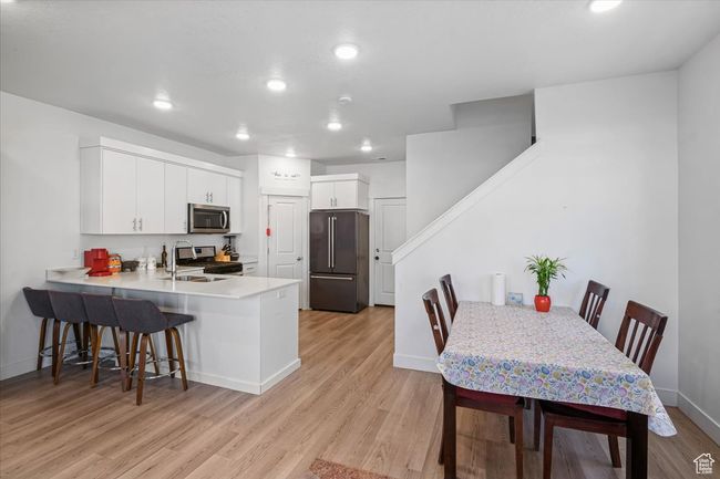 Kitchen featuring stainless steel appliances, a kitchen bar, light wood-style flooring, a peninsula, and baseboards | Image 6