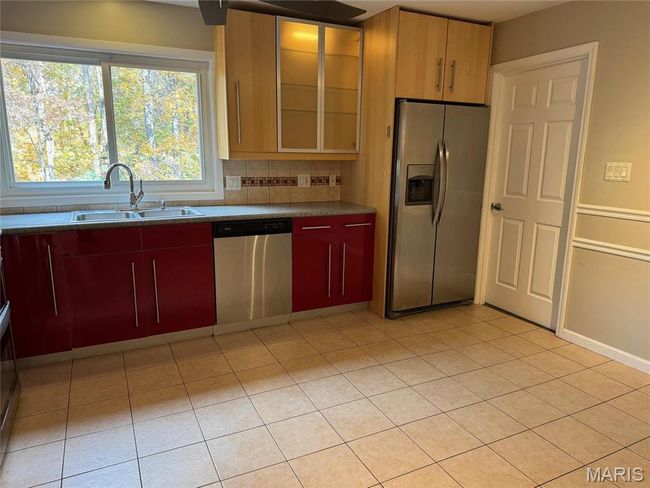 Kitchen featuring decorative backsplash, appliances with stainless steel finishes, sink, and light tile patterned floors | Image 6