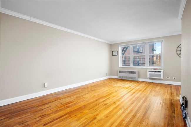 Unfurnished room with radiator heating unit, wood-type flooring, crown molding, and a wall mounted AC | Image 5