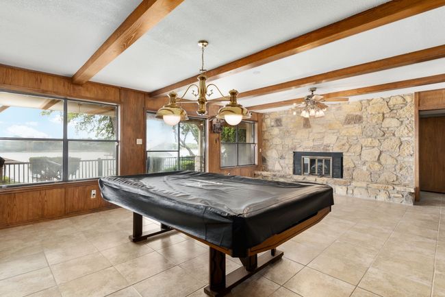 Playroom with light tile patterned floors, beam ceiling, wood walls, and pool table | Image 26