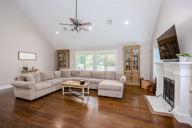 Living room with ceiling fan, high vaulted ceiling, a high end fireplace, dark wood-style floors, and recessed lighting | Image 9