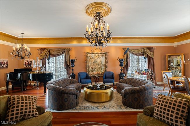Another view of the family room featuring wood finished floors, a chandelier, and ornamental molding with lighting. | Image 16