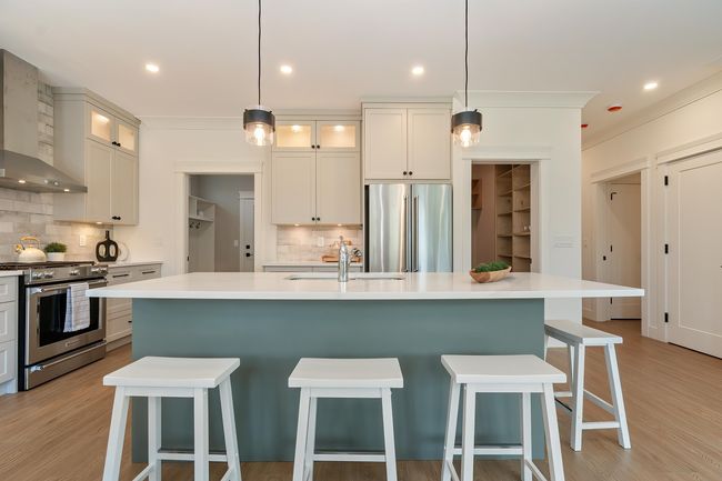 Kitchen featuring stainless steel appliances, wall chimney exhaust hood, tasteful backsplash, a kitchen island with sink, and recessed lighting | Image 5