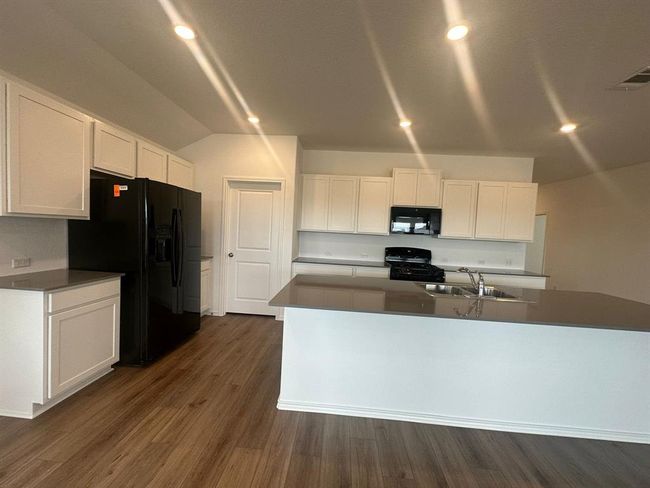 Kitchen with black appliances, white cabinetry, dark wood-style floors, dark countertops, and vaulted ceiling | Image 16