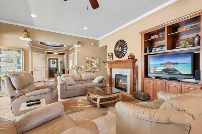 Living room with crown molding, ceiling fan, a high end fireplace, light tile patterned floors, and recessed lighting | Image 4