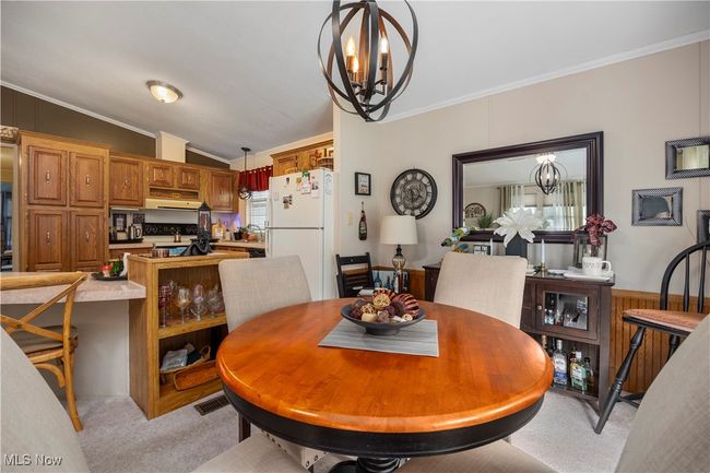 Dining space with a chandelier, light colored carpet, ornamental molding, and vaulted ceiling | Image 21
