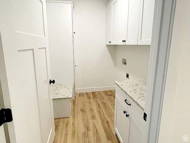 Washroom with cabinet space, baseboards, hookup for a washing machine, hookup for an electric dryer, and light wood-style floors | Image 10