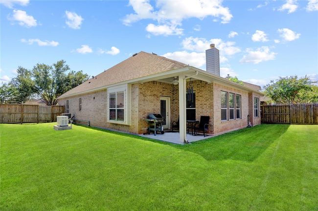 This is a single-story brick home featuring a well-maintained lawn, a covered patio area, and a privacy fence surrounding the backyard. | Image 26
