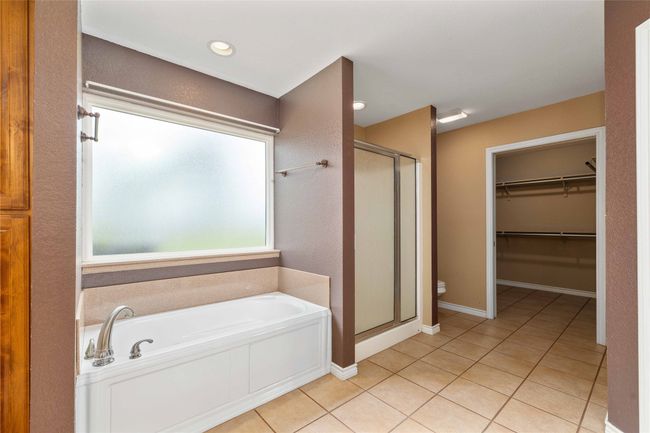 Full bathroom featuring a shower stall, a bath, tile patterned flooring, and a spacious closet | Image 12