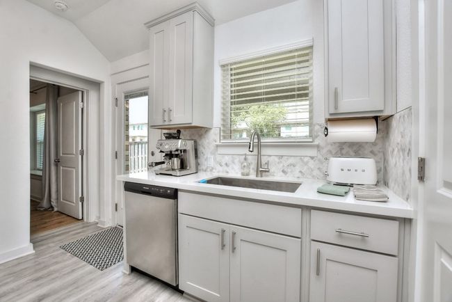 Kitchen with tasteful backsplash, light countertops, light wood-style floors, stainless steel dishwasher, and a sink | Image 18