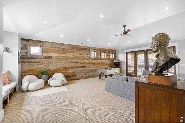 Carpeted living room featuring an accent wall, a ceiling fan, vaulted ceiling, recessed lighting, and wood walls | Image 55