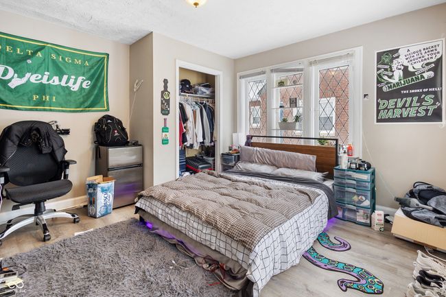 bedroom with freestanding refrigerator, wood finished floors, a closet, and baseboards | Image 13