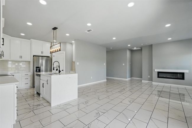 Kitchen with a sink, open floor plan, marble finish floor, light countertops, and baseboards | Image 4