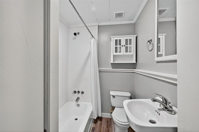 Bathroom with crown molding, shower / bath combination with curtain, and wood finished floors | Image 16