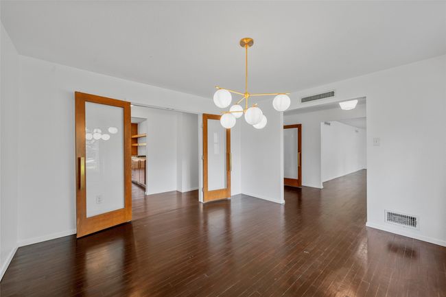 Spare room featuring wood finished floors, a chandelier, and baseboards | Image 8