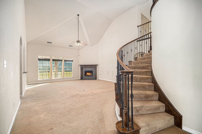 Stairs featuring carpet, high vaulted ceiling, a ceiling fan, a tiled fireplace, and baseboards | Image 6