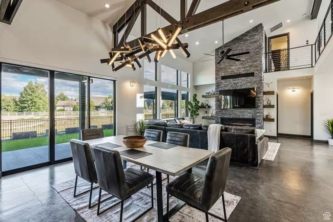 Dining area featuring visible vents, beamed ceiling, concrete flooring, and a stone fireplace | Image 10