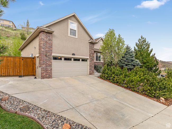 View of home's exterior featuring stucco siding, concrete driveway, fence, and brick siding | Image 5