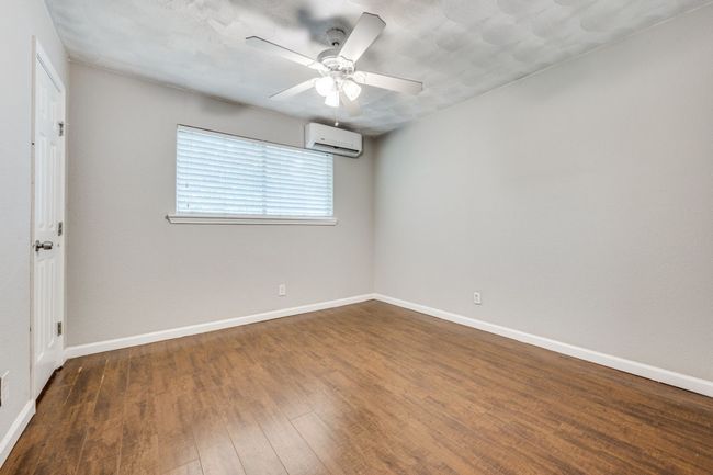 Empty room featuring a wall mounted air conditioner, ceiling fan, and wood finished floors | Image 9