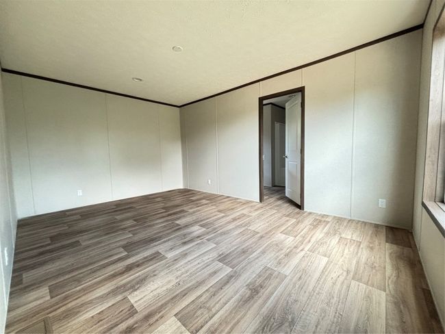 Empty room with ornamental molding, a decorative wall, and light wood finished floors | Image 7