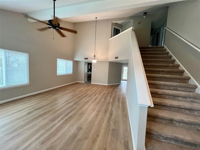 Stairs with high vaulted ceiling, baseboards, wood finished floors, and a ceiling fan | Image 4
