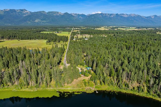 Aerial view of private, wooded retreat with mountain views, paved road access, and lake frontage with dock | Image 12