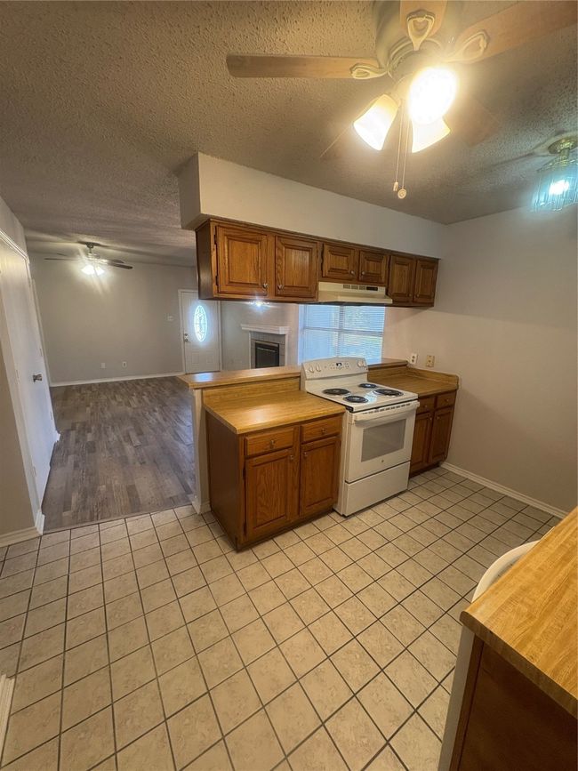 Kitchen with range, ventilation hood, ceiling fan, and light tile patterned floors | Image 7