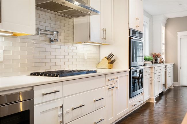 Convenient pot filler, 6 burner gas cook top, double ovens and elegant white glass subway tile backsplash make this kitchen a dream to cook in and entertain friends and family! | Image 10