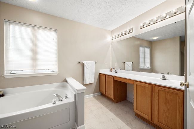 Bathroom featuring dual vanity, a textured ceiling, a washtub, and tile flooring | Image 22