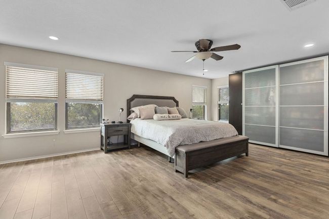 Bedroom with multiple windows, wood finished floors, recessed lighting, baseboards, and a ceiling fan | Image 4