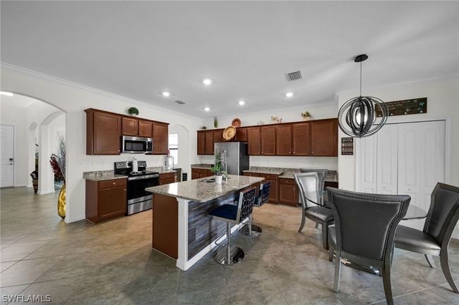 Kitchen featuring a breakfast bar area, stainless steel appliances, sink, light tile patterned floors, and a kitchen island | Image 13