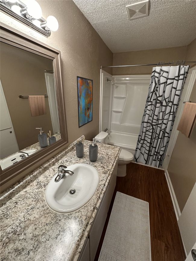 Bathroom with vanity, a textured ceiling, toilet, visible vents, and wood finished floors | Image 5