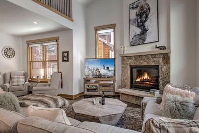 Living room featuring a stone fireplace, hardwood / wood-style floors, and lofted ceiling | Image 2