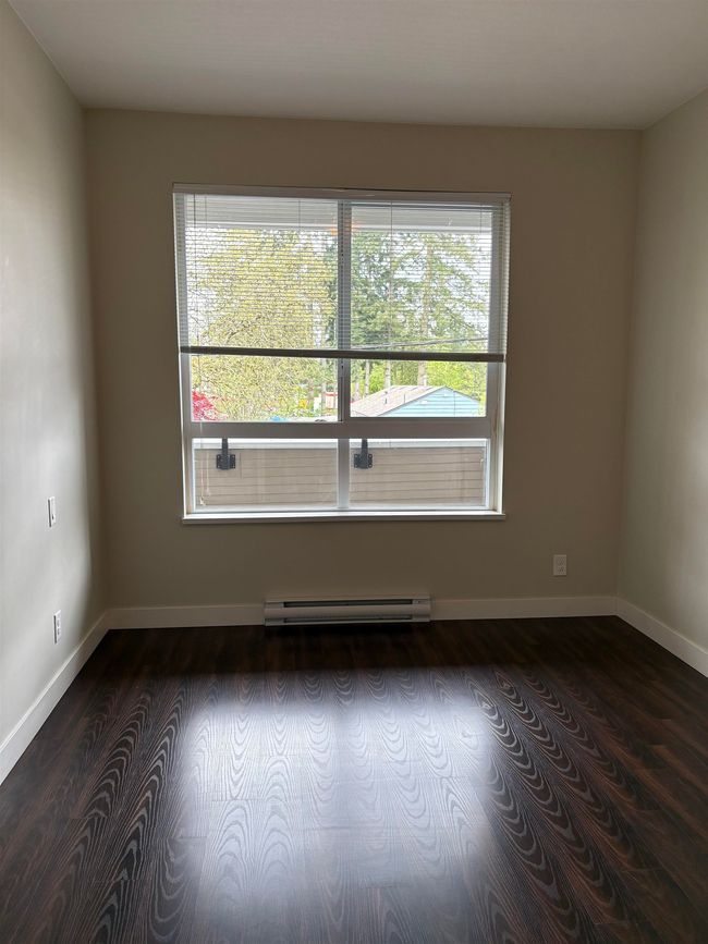 Empty room with a wealth of natural light, dark wood-style flooring, baseboard heating, and baseboards | Image 7