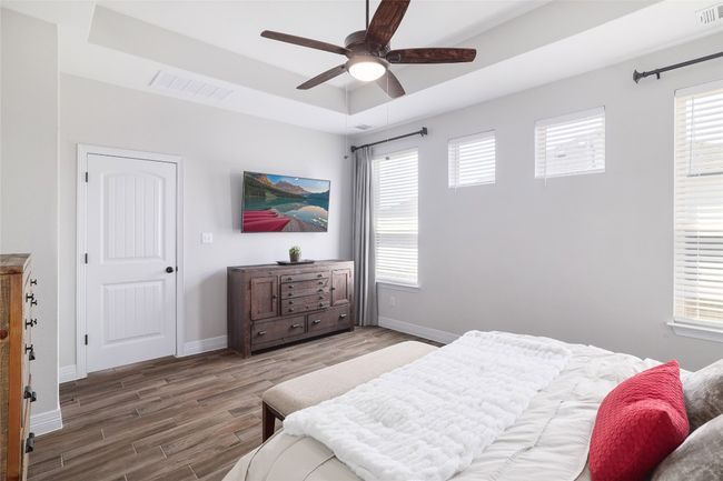 Bedroom with a tray ceiling, multiple windows, and wood finished floors | Image 20